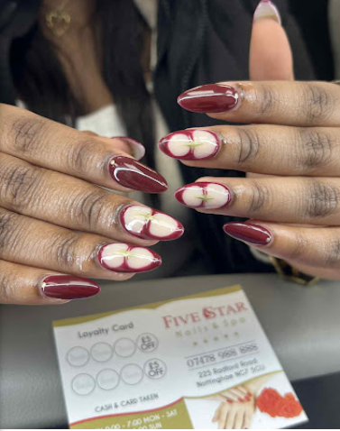 Deep burgundy nails with hand-painted white floral detail by Five Star Nails
